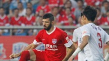 Chongqing Lifan forward Emanuel Gigliotti (L) competes for the ball against Shanghai SIPG's Kim Ju-young