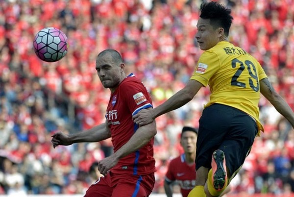 Chongqing Lifan defender Goran Milovic (L) competes for the ball against Guanzhou Evergrande's Gao Lin