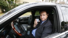 Uber limousine driver holding up his iPhone with the Uber application open
