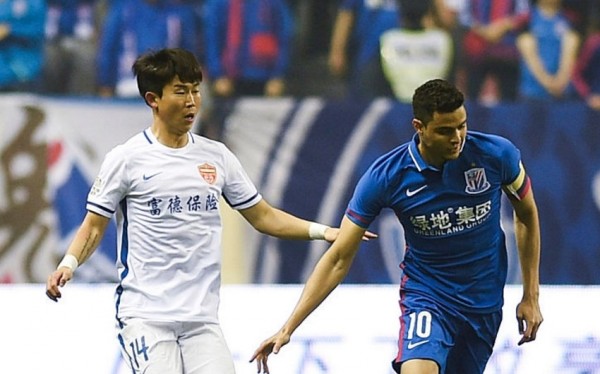 Yanbian Funde midfielder Yoon Bit-garam (L) competes against Shanghai Shenhua's Giovanni Moreno. 
