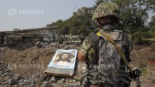A Ukrainian serviceman stands near a damaged board with an image of Jesus Christ, which was left by pro-Russian separatists, at a check point in the town of Vuhlehirsk, Donetsk region, August 14, 2014. 