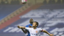 Yanbian Funde defender Cui Min (in white) competes for the ball against Shanghai Shenhua's Demba Ba