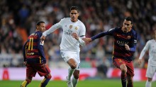 Real Madrid center back Raphael Varane competes for the ball against Barcelona's Sergio Busquets and Neymar