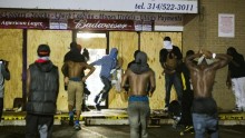 Masked individuals carried items out of a liquor store in Ferguson, Mo., early Saturday. 