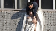 A 22-year-old woman in a wedding gown is grabbed by Guo Zhongfan, a local community officer, as she attempts to kill herself by jumping out of a seven-storey residential building in Changchun, China in 2011.