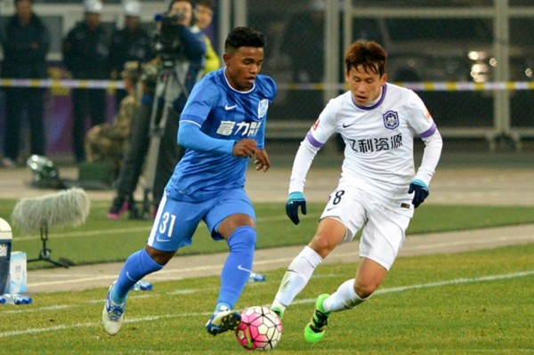 Guangzhou R&F midfielder Renatinho (L) competes for the ball against Tianjin Teda's Hu Rentian