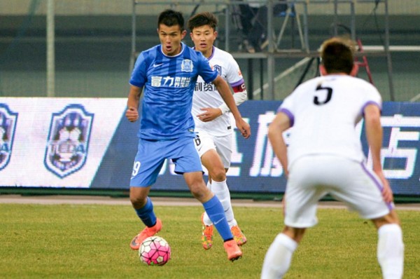 Guangzhou R&F striker Xiao Zhi drives against Tianjin Teda defenders