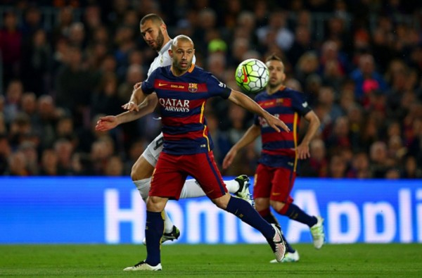 Barcelona defender Javier Mascherano competes for the ball against Real Madrid's Karim Benzema