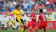 Guangzhou Evergrande attacking midfielder Ricardo Goulart passes the ball off two Chongqing Lifan defenders