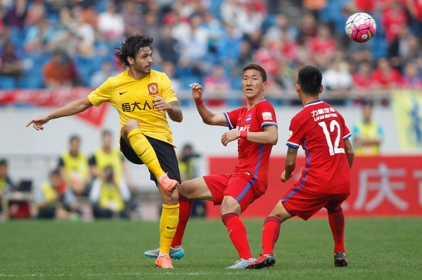 Guangzhou Evergrande attacking midfielder Ricardo Goulart passes the ball off two Chongqing Lifan defenders