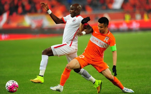 Liaonin Whowin striker James Chamanga (L) competes for the ball against Shandong Luneng's Hao Junmin