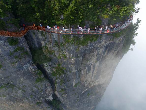 Aerial view of tourists walking on the 100-meter-long and 1.6-meter-wide glass skywalk clung the cliff of Tianmen Mountain (or Tianmenshan Mountain) in Zhangjiajie National Forest Park on August 1, 2016 in Zhangjiajie, Hunan Province of China.