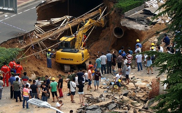 This photo taken on August 2, 2016 shows rescuers searching for missing people after a giant sinkhole opened up on a road in Zhengzhou, in central China's Henan province