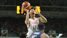 Chinese forward Yi Jianlian shoots over Carmelo Anthony and Draymond Green of Team USA