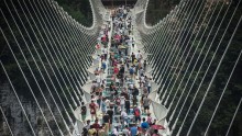 Visitors cross the world's highest and longest glass-bottomed bridge above a valley in Zhangjiajie in China's Hunan Province on August 21, 2016.