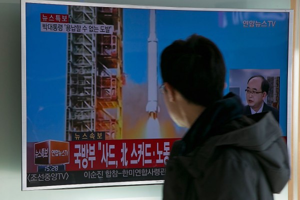People watch a television screen showing a breaking news on North Korea's long-range rocket launch