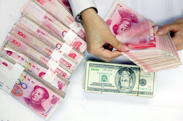 A clerk counts stacks of Chinese yuan and U.S. dollars at a bank on July 22, 2005 in Shanghai, China. 