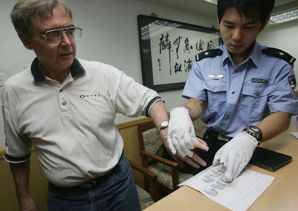 A foreign affairs policeman helps a U.S. citizen to print his fingerprints.