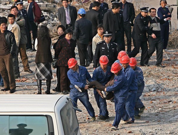 Corrupt officials being escorted to a van by construction workers.