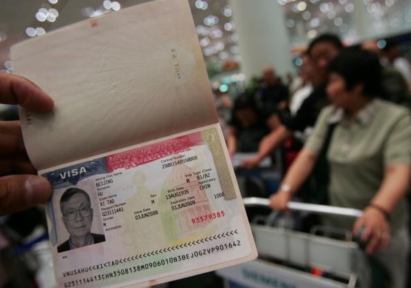 A U.S. visa is shown by a tourist as the first group of Chinese tourists set out to visit US at the Beijing Capital International Airport on June 17, 2008 in Beijing, China. 