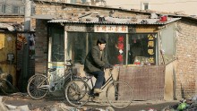  A cyclist rides past a public telephone booth in a poor slum area on January 2, 2005 in Beijing, China. 