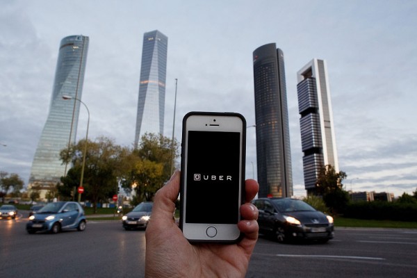 In this Photo Illustration a smart phone displays a picture with the logo of the news taxi app 'Uber' near the Cuatro Torres 'Four Towers' business area on October 14, 2014 in Madrid, Spain. 