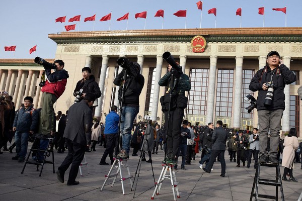  Photo-journalists standing on stools in front of the Great Hall of the People.